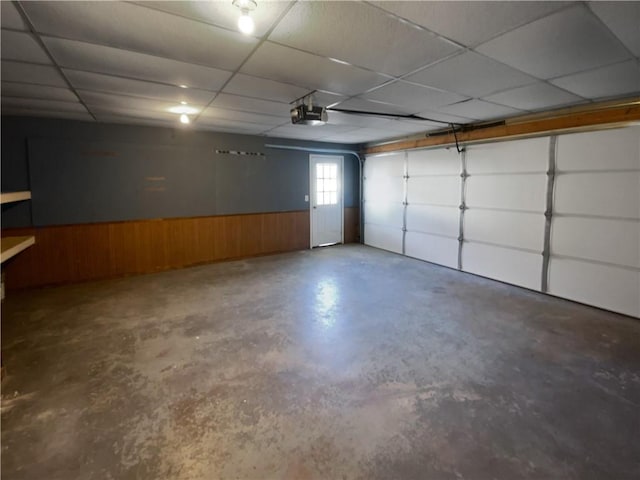 garage with a wainscoted wall, wooden walls, and a garage door opener