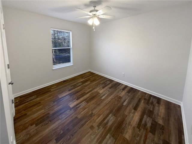 empty room with dark wood-type flooring, a ceiling fan, baseboards, and visible vents