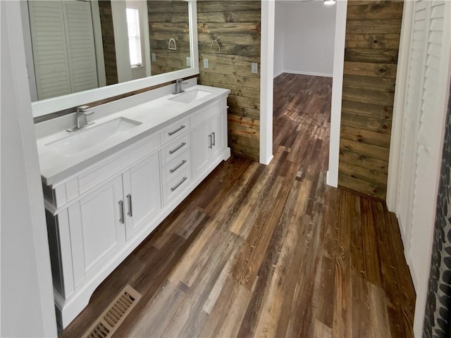 bathroom with a sink, wood finished floors, and wood walls