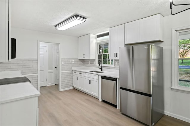 kitchen with white cabinets, a textured ceiling, appliances with stainless steel finishes, and sink