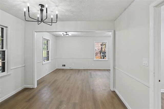 spare room featuring hardwood / wood-style flooring, a notable chandelier, and a textured ceiling