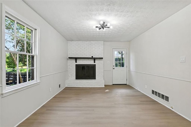 unfurnished living room featuring hardwood / wood-style flooring, a fireplace, and a textured ceiling