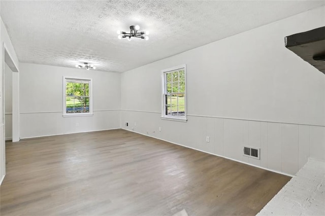 unfurnished room featuring a textured ceiling, plenty of natural light, and dark wood-type flooring