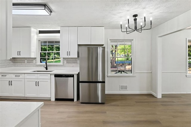 kitchen featuring stainless steel appliances, sink, white cabinetry, and a healthy amount of sunlight