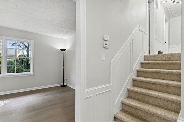 staircase featuring wood-type flooring and a textured ceiling