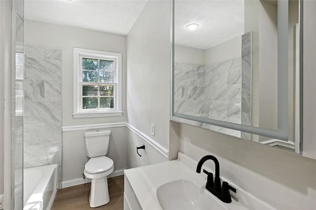 full bathroom featuring hardwood / wood-style floors, vanity, toilet, and tiled shower / bath