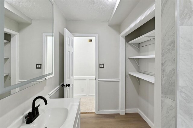 bathroom with a textured ceiling, vanity, and hardwood / wood-style flooring