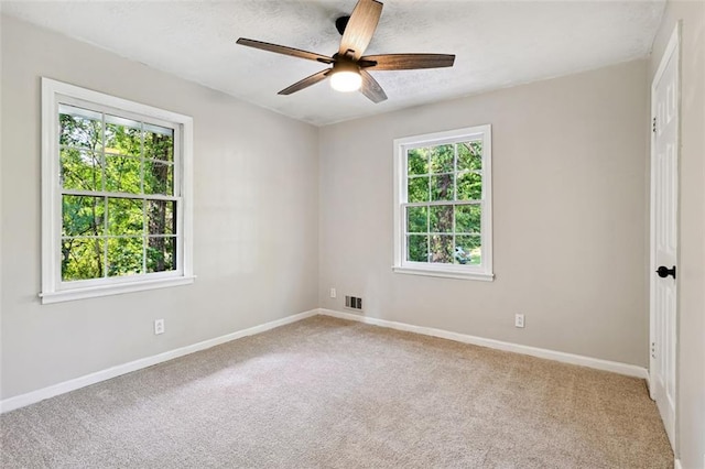 spare room featuring carpet, ceiling fan, and a wealth of natural light