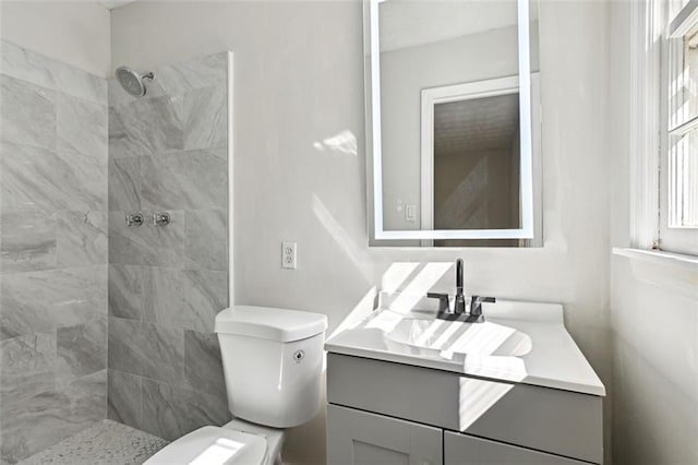 bathroom with tiled shower, vanity, and toilet