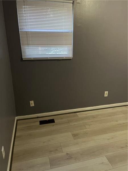 unfurnished room featuring visible vents, light wood finished floors, and baseboards