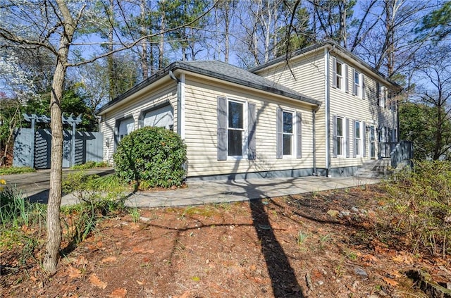 view of side of home featuring a garage and fence