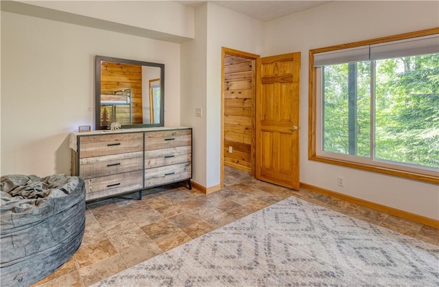 bedroom featuring stone finish flooring, multiple windows, and baseboards