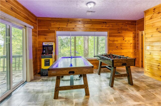 rec room featuring wood walls, visible vents, and a textured ceiling