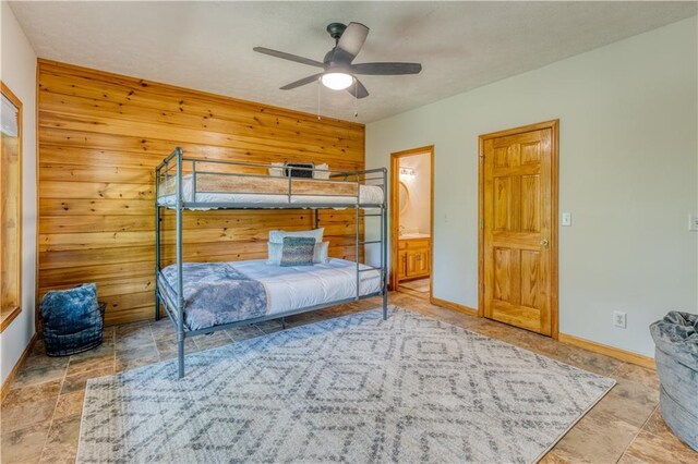 bedroom featuring ceiling fan, stone finish flooring, connected bathroom, and baseboards