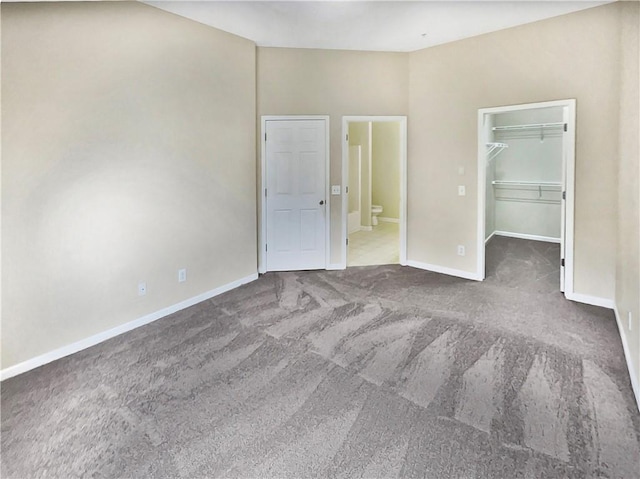 unfurnished bedroom with a closet, carpet flooring, a walk in closet, and ensuite bath