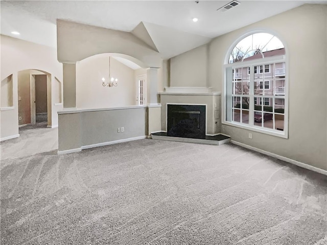 unfurnished living room featuring light colored carpet, lofted ceiling, and a notable chandelier