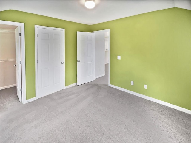 unfurnished bedroom featuring vaulted ceiling, light carpet, a closet, and a spacious closet