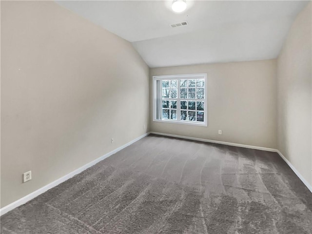 carpeted spare room featuring vaulted ceiling