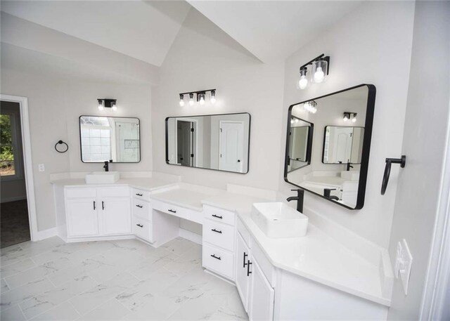 bathroom featuring two vanities, marble finish floor, a sink, and vaulted ceiling