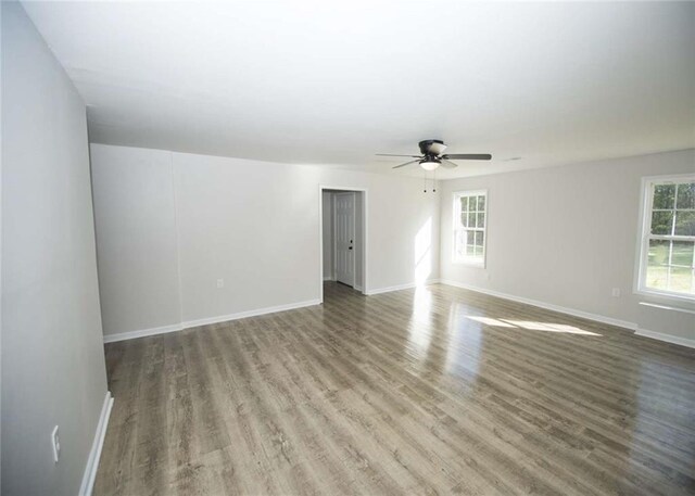 spare room with baseboards, wood finished floors, and ceiling fan
