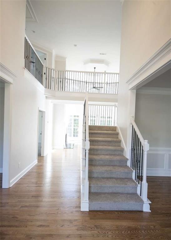 stairs with a towering ceiling, baseboards, and wood finished floors