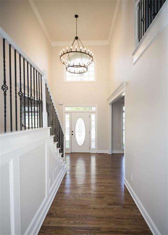 foyer entrance featuring crown molding, wood finished floors, an inviting chandelier, and baseboards