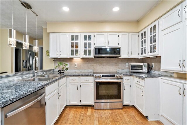 kitchen with appliances with stainless steel finishes, white cabinetry, light hardwood / wood-style flooring, decorative light fixtures, and sink