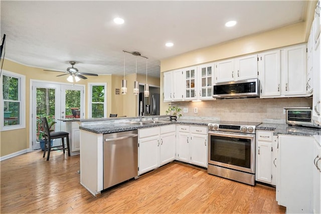 kitchen with pendant lighting, white cabinets, kitchen peninsula, light hardwood / wood-style flooring, and stainless steel appliances