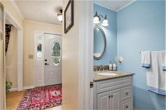 bathroom with ornamental molding, wood-type flooring, and vanity