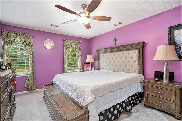 bedroom with a textured ceiling, ceiling fan, and light colored carpet