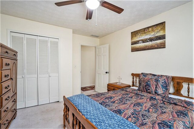 carpeted bedroom with a textured ceiling, ceiling fan, and a closet