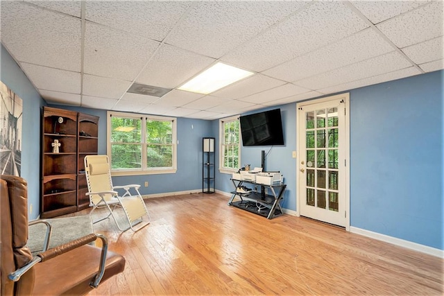 living area with wood-type flooring and a paneled ceiling