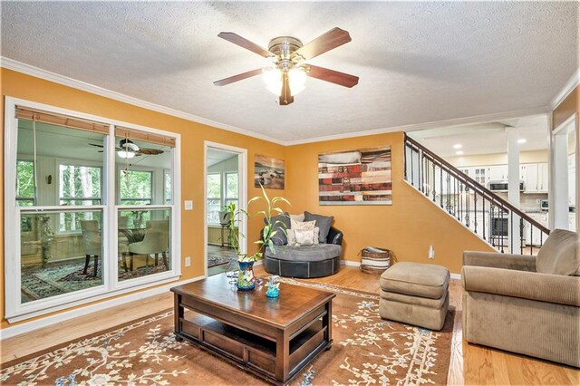 living room with a textured ceiling, crown molding, hardwood / wood-style floors, and ceiling fan