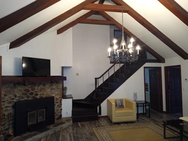 living room with lofted ceiling with beams, dark hardwood / wood-style flooring, a chandelier, and a fireplace