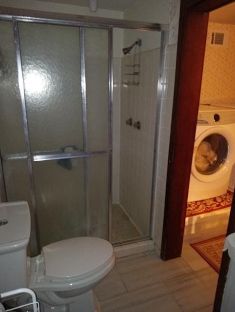 bathroom featuring walk in shower, tile patterned floors, toilet, and washer / dryer