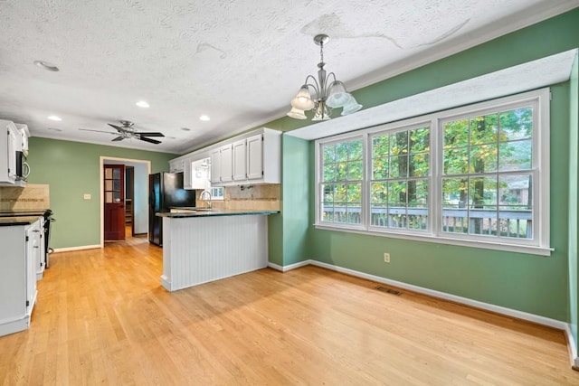 kitchen with visible vents, freestanding refrigerator, white cabinets, stainless steel microwave, and tasteful backsplash