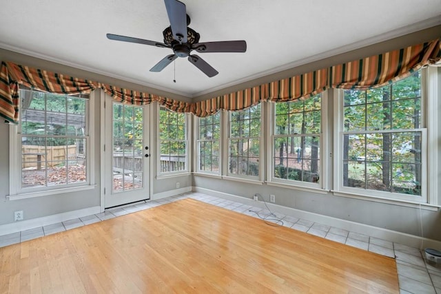 unfurnished sunroom with a ceiling fan and a healthy amount of sunlight