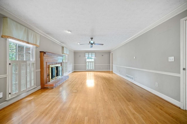 unfurnished living room featuring visible vents, wood finished floors, a brick fireplace, and ornamental molding