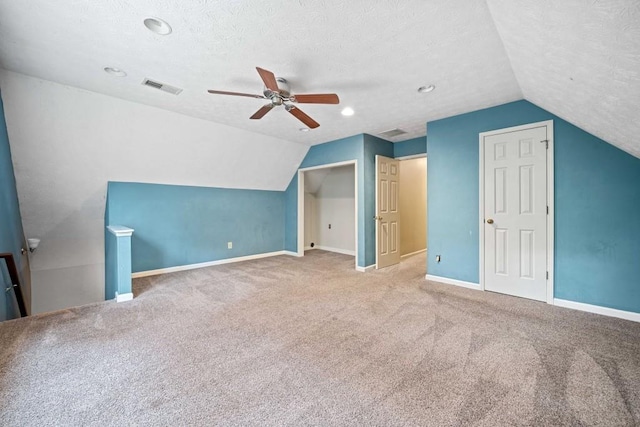 additional living space with baseboards, visible vents, a textured ceiling, and lofted ceiling