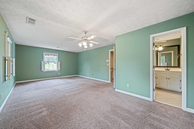 unfurnished bedroom with visible vents, baseboards, carpet flooring, a textured ceiling, and a sink