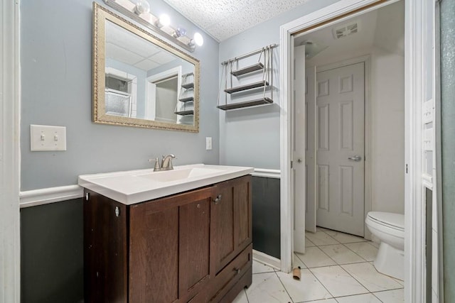 half bathroom with vanity, toilet, visible vents, and a drop ceiling