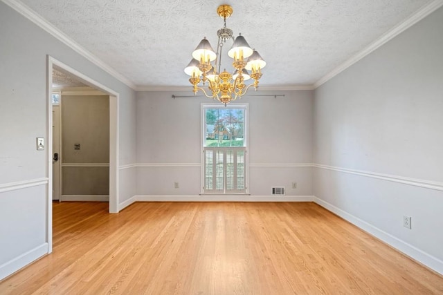 unfurnished room featuring a notable chandelier, visible vents, light wood-type flooring, and ornamental molding