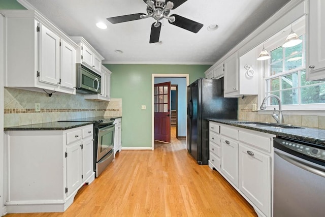 kitchen featuring light wood-type flooring, ornamental molding, appliances with stainless steel finishes, white cabinets, and a sink