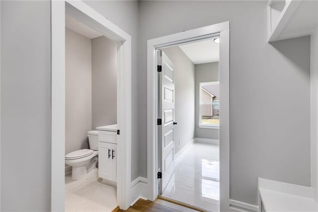 bathroom featuring marble finish floor, baseboards, toilet, and vanity