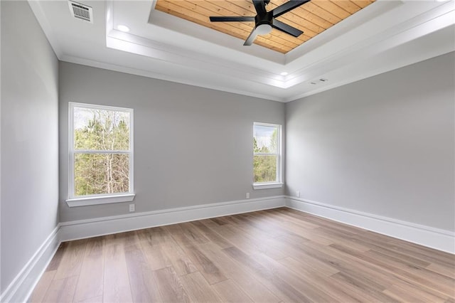 unfurnished room featuring crown molding, baseboards, a raised ceiling, visible vents, and wood finished floors