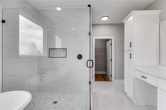 full bath with vanity, a marble finish shower, a spacious closet, a soaking tub, and marble finish floor