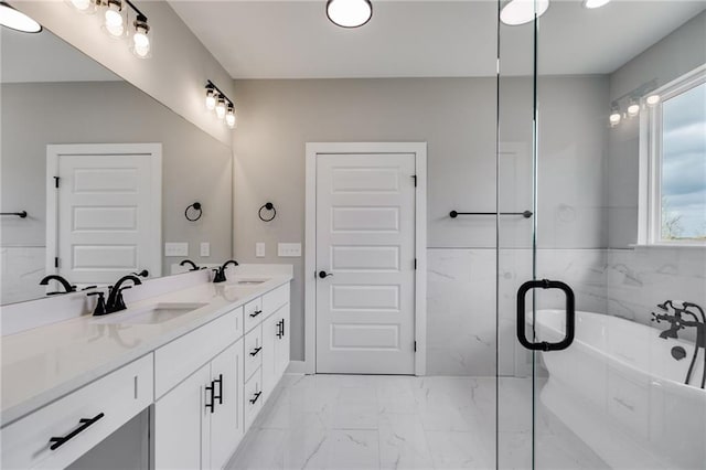 bathroom featuring marble finish floor, a sink, a freestanding tub, and double vanity