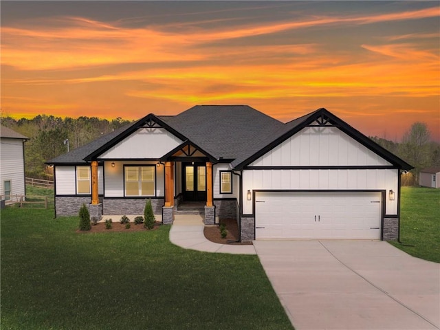 view of front facade with stone siding, concrete driveway, an attached garage, board and batten siding, and a yard