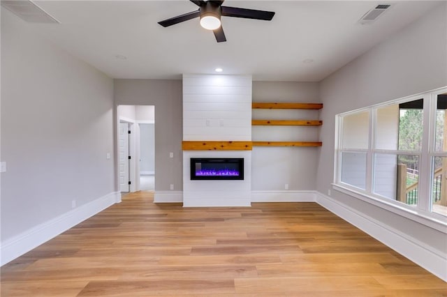 unfurnished living room with baseboards, a fireplace, light wood-style flooring, and a ceiling fan