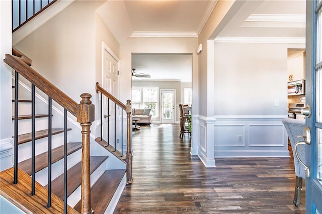 entrance foyer with a decorative wall, a wainscoted wall, dark wood-style flooring, ornamental molding, and stairway